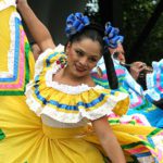 Woman in colorful traditional dress dancing joyfully outdoors.